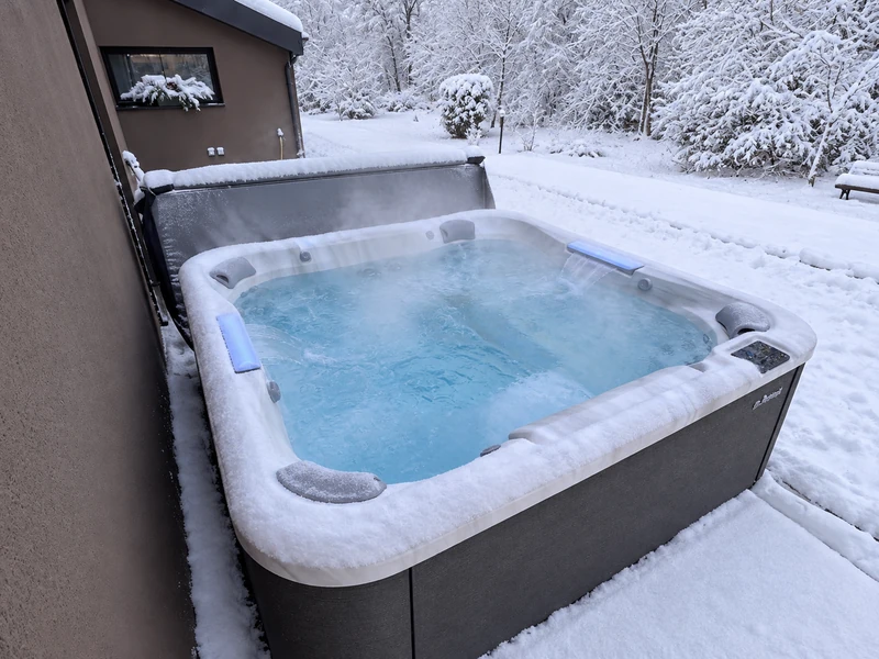 Spa Jacuzzi® en eau chaude et fumant, au milieu d'un jardin enneigé